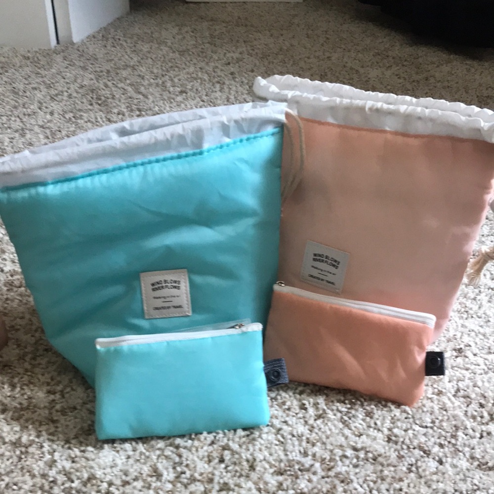 Two “Wind Blows River Flows” cosmetic bags. Each has draw string top.